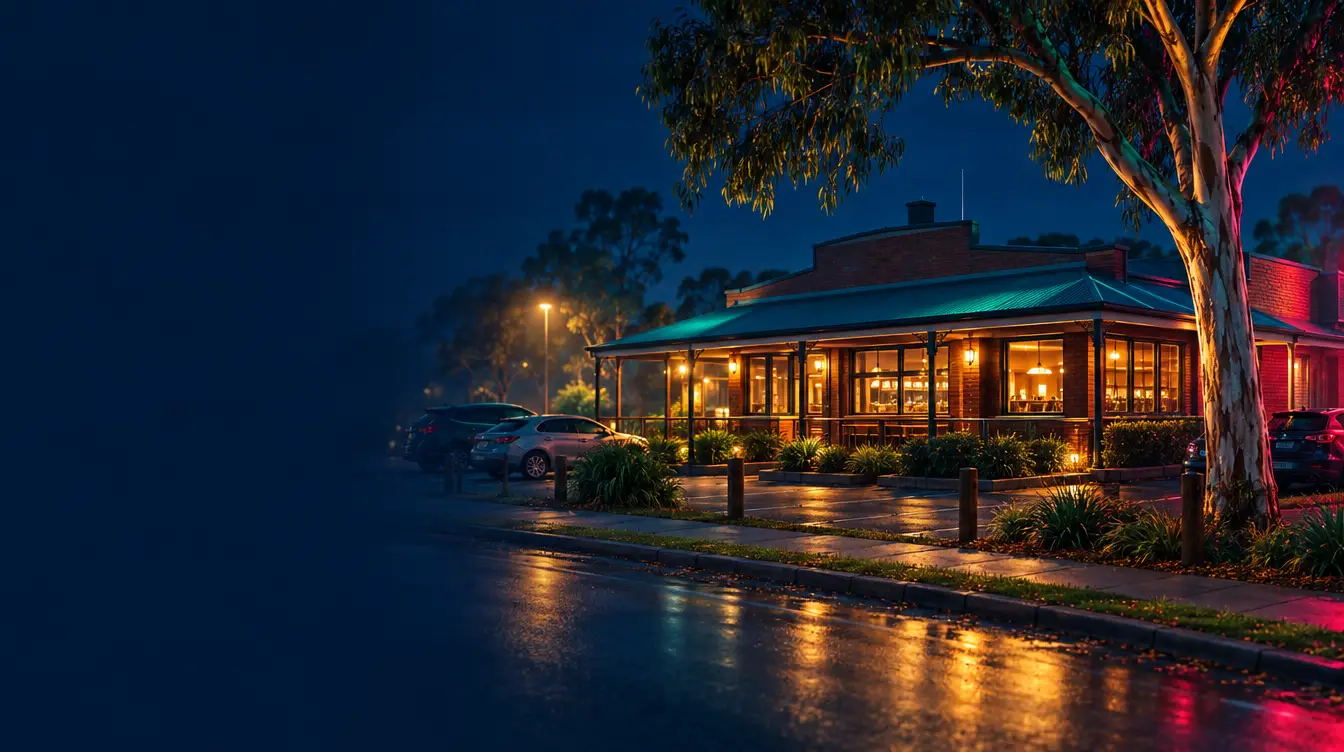 Suburban brick pub with a veranda and warm lit windows at night, parked cars and a gum tree